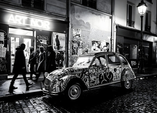 Tableau photo noir et blanc d’une Citroën 2CV en décor urbain
