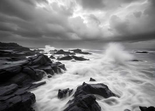 Tableau photo noir et blanc de vagues et rochers sous un ciel chargé

